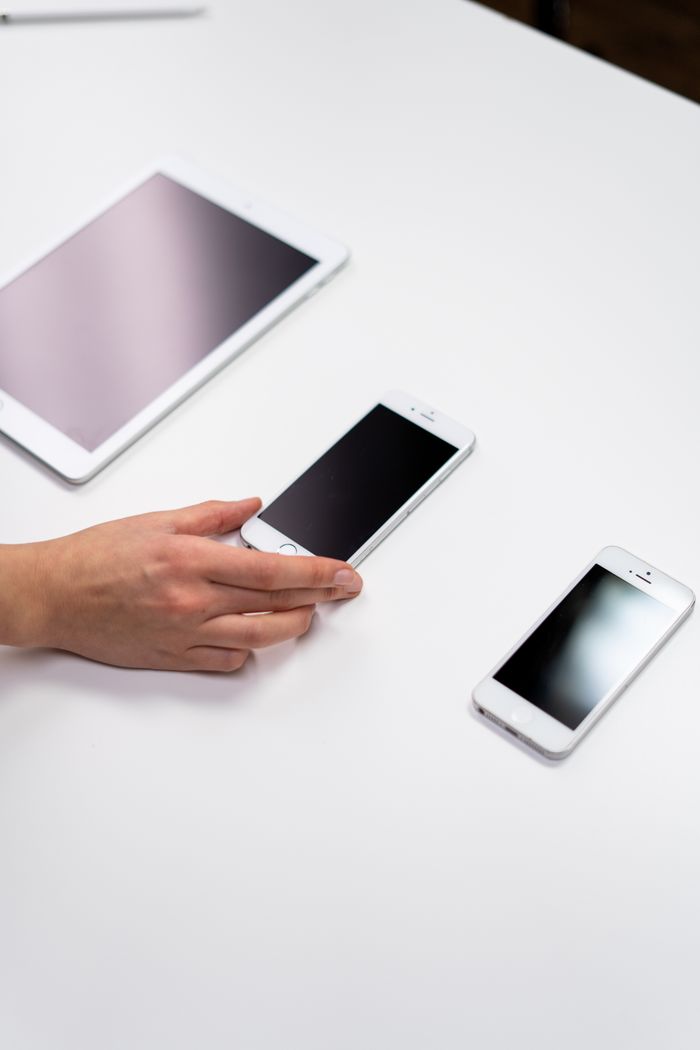 who-we-are Vue de dessus d’un ensemble minimaliste présentant une tablette et des smartphones sur une surface blanche.